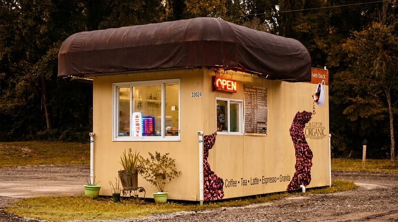 Yellow organic coffee stand with an "OPEN" sign, menu, and coffee bean graphics.