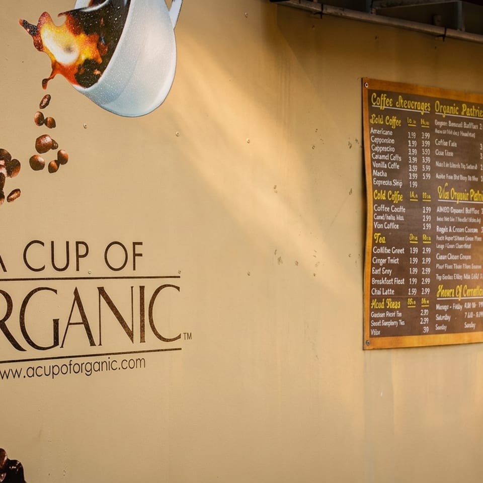 A Cup of Organic coffee stand with a large coffee bean graphic, menu board, and service window.